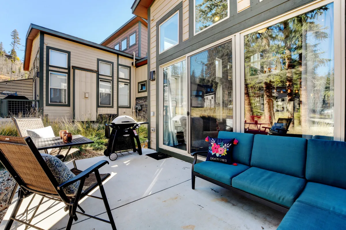 A relaxed outdoor seating area with a grill and large windows looking into the home, suggesting a seamless indoor-outdoor connection. The space is ideal for both casual barbecues and quiet moments, enveloped in a tranquil atmosphere that encourages unwinding and connecting with nature.