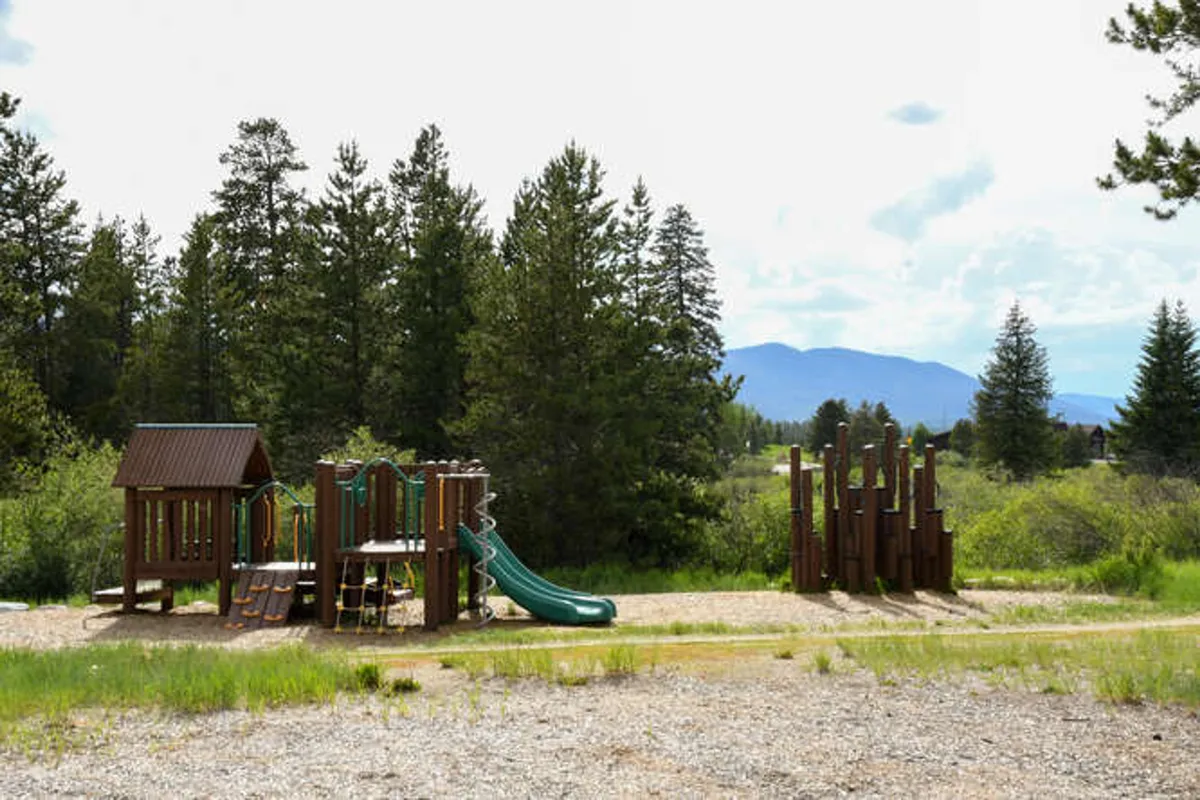 A vibrant playground scene with slides and climbing equipment, set in a cheerful, outdoor environment. The area is designed for children’s play and family bonding, linking the property’s patio to nearby recreational amenities.