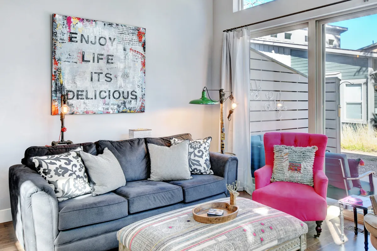A playful and comfortable corner of the living area, featuring colorful artwork, a plush sofa, and a distinct pink armchair. The mood is lively yet relaxed—perfect for socializing, enjoying refreshments, or lounging after a day of mountain adventures.