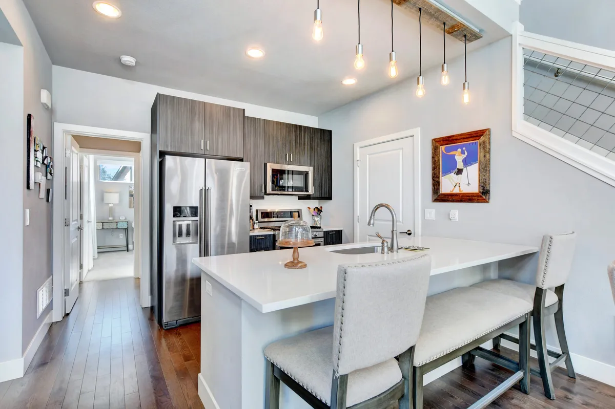 A bright kitchen featuring a central island with bar stools, stainless steel appliances, and a decorative art piece. The open space is perfect for both meal prep and casual dining, encouraging interaction and togetherness.
